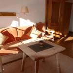 Wohnzimmer mit Sofa, Tisch und Lampen. Holztür und Fliesenboden sichtbar.