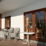 Terrasse mit Tisch, Stühlen und Sonnenschirm. Durchgehende Glasfront zur Küche.