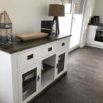 Weißer Sideboard mit dunklem Holzoberflächen und Glasfronten, daneben Küche mit Backofen.