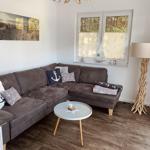 Ein Wohnzimmer mit braunem Sofa, runden Tisch und Fenster mit Jalousie.