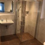 Badezimmer mit Dusche, Waschbecken und Spiegel