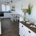 Küche mit Essbereich und Wohnbereich. Holzboden, weiße Möbel, moderne Beleuchtung.