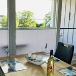 Dining table with placemats and wine bottle by window with water view.