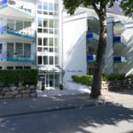 White multi-family house with balconies and entrance area.