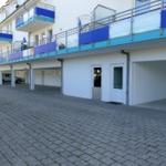 Building with balconies and parking spaces on the ground floor.