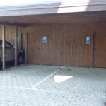 Parking area with wooden wall and two doors for apartments.