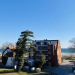 Red multi-family house with sea view and parking lot.