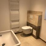 Badezimmer mit Waschbecken, Toilette und Heizkörper.