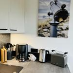 Kitchenette with coffee maker, kettle, and toaster. Wall art shows a telescope.