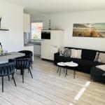 Living and dining area with sofa, table, and kitchenette.