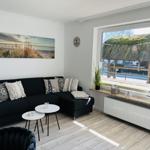 Living room with black sofa, view of thatched roof through window