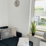 Black seating area with cushions, wall clock, and plant by window.