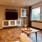 Wohnzimmer mit Holzboden, Fernseher und Fenster
