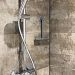 Duschkopf mit Handbrause und Wandhalterung in Dusche mit Steinfliesen