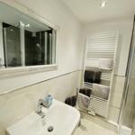Badezimmer mit Waschbecken, Spiegel, Dusche und Handtuchhalter.
