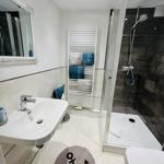 Badezimmer mit Dusche, Waschbecken und Heizkörper mit Handtüchern.