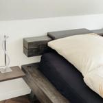 Schlafzimmer mit Holzbett, Wandlampe und Holzboden.