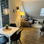 Wohnung mit Essbereich, Sofa und TV. Holzboden und große Fenster.