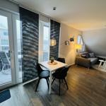 Wohnung mit Essbereich, Sofa und Balkon. Holzboden und große Fenster.