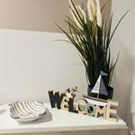 Willkommensdekoration mit Boot und Pflanze auf einem Tisch