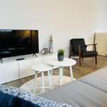 Wohnzimmer mit Sofa, Fernseher und Sitzgruppe.