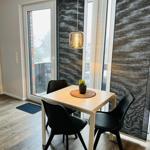 Esstisch mit vier Stühlen vor großem Fenster mit Blick auf Balkon.