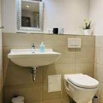 Bad mit Waschbecken, Spiegel, Toilette und Pflanze.