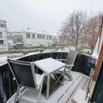 Terrasse mit Tisch und zwei Stühlen, bedeckt mit Schnee. Blick auf Wohnhäuser und Bäume.