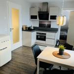 Küche mit Essbereich, weiße Schränke, schwarze Arbeitsfläche und Retro-Kühlschrank.