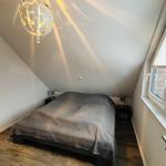 Schlafzimmer mit Dachschrägen, Bett, Nachttischen und Fenster.