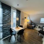 Wohnung mit Essbereich, Sofa und Balkon. Holzboden und große Fenster.