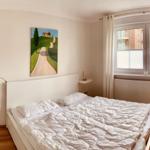 Bedroom with double bed, window, and wooden floor.