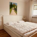 Bedroom with bed, wall painting, and window with blinds.