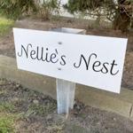 Schild mit der Aufschrift Nellies Nest im Garten