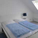 Schlafzimmer mit Doppelbett, zwei Nachttischen und Dachfenster.