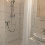 Badezimmer mit Dusche, Waschbecken und Spiegel.