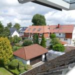 Panorama aus dem Dachfenster: Haus mit rotem Dach, Garten und Blick aufs Meer.