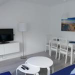 Wohn- und Essbereich mit TV, Tisch, Stühlen und Wandbild.