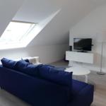Wohnzimmer mit blauem Sofa, TV und Dachfenster.