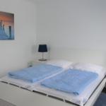 Schlafzimmer mit Doppelbett, zwei Nachttischen und Wandbild.