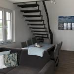 Living and dining area with staircase and window. Sofa, table, and chairs are visible.