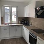 Kitchen with white cabinets, wooden countertop, and window overlooking outside.