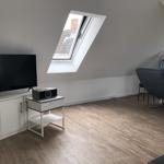 Attic room with TV, window, and seating area.