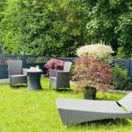 Garten mit Liegestühlen, Tisch und Stühlen, Pflanzen und Zaun.