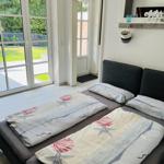 Schlafzimmer mit Doppelbett, Fenster zur Terrasse und Spiegel an der Wand.
