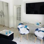 Wohnzimmer mit TV, zwei Stühlen und Tisch. Hintergrund: Tür und Wanddekoration.