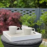 Auf einem Tisch stehen zwei Tassen und eine Pflanze im Garten.