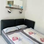 Zimmer mit Bett, Spiegel und Wandregal mit Körben.