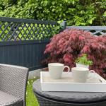 Gartenbereich mit Stuhl, Tisch und zwei Tassen auf einem Tablett.