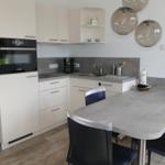 Kitchen with dining area, white cabinets, and gray worktop.